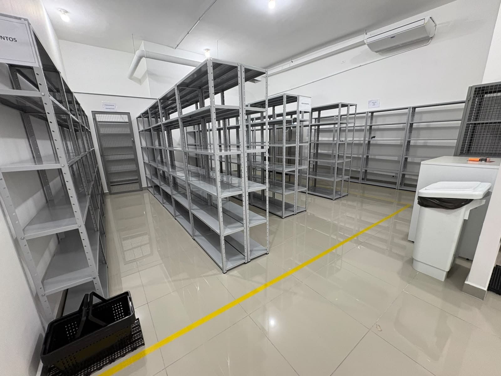 Estoque principal do centro de distribuição da Primmera Care, com estantes metálicas e demarcação de piso.